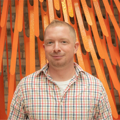 Person smiling with an orange artistic backdrop.