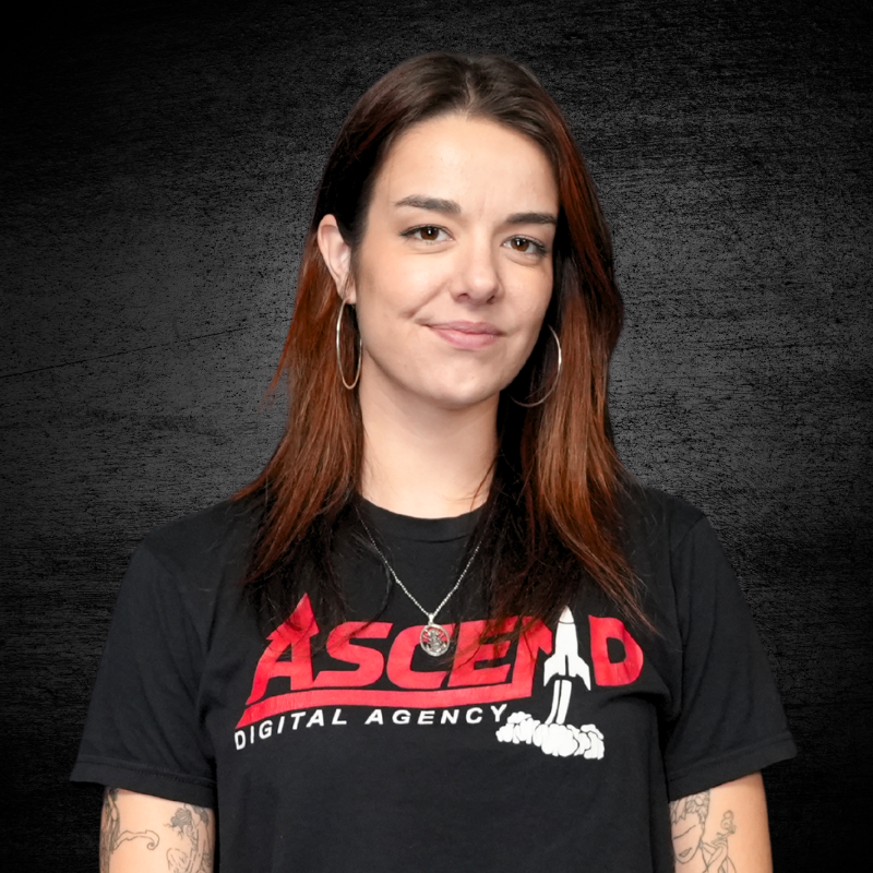 Woman with brown hair in black T-shirt against dark background