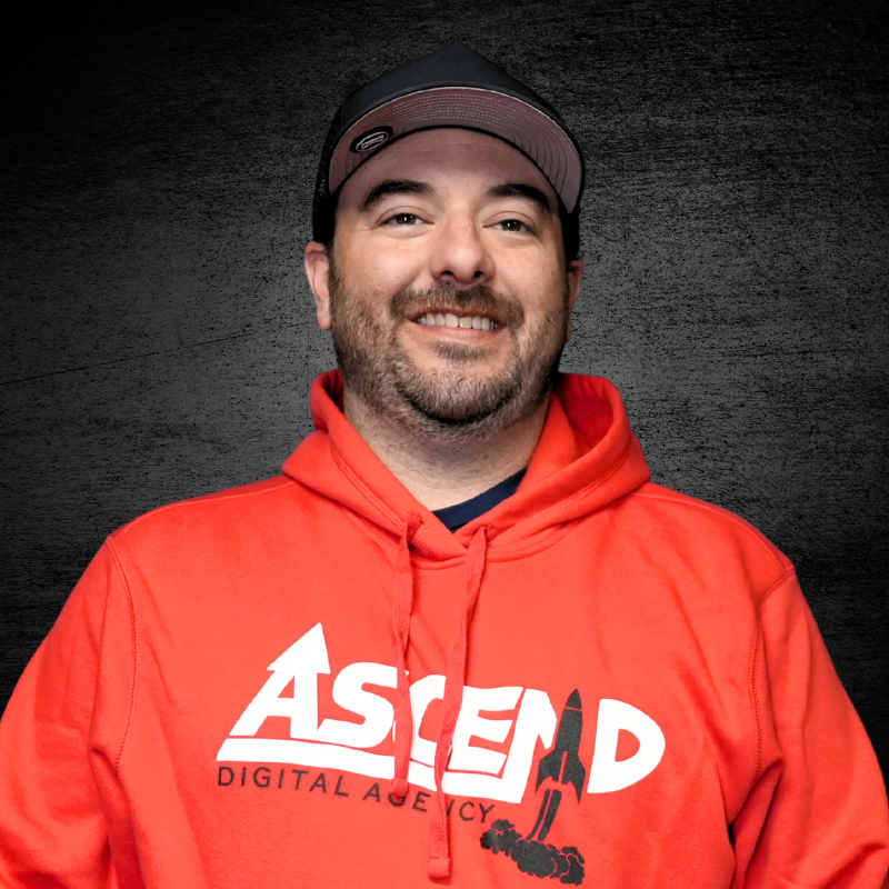 Smiling man in red hoodie with Ascend Digital Agency logo.