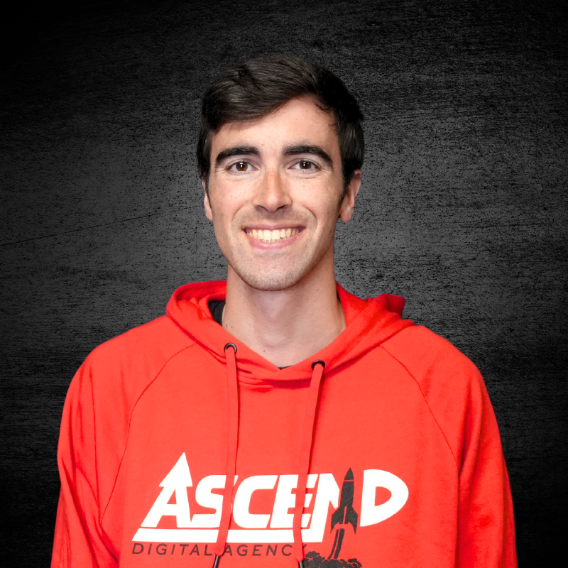 Man smiling in red Ascend Digital Agency hoodie against dark background.