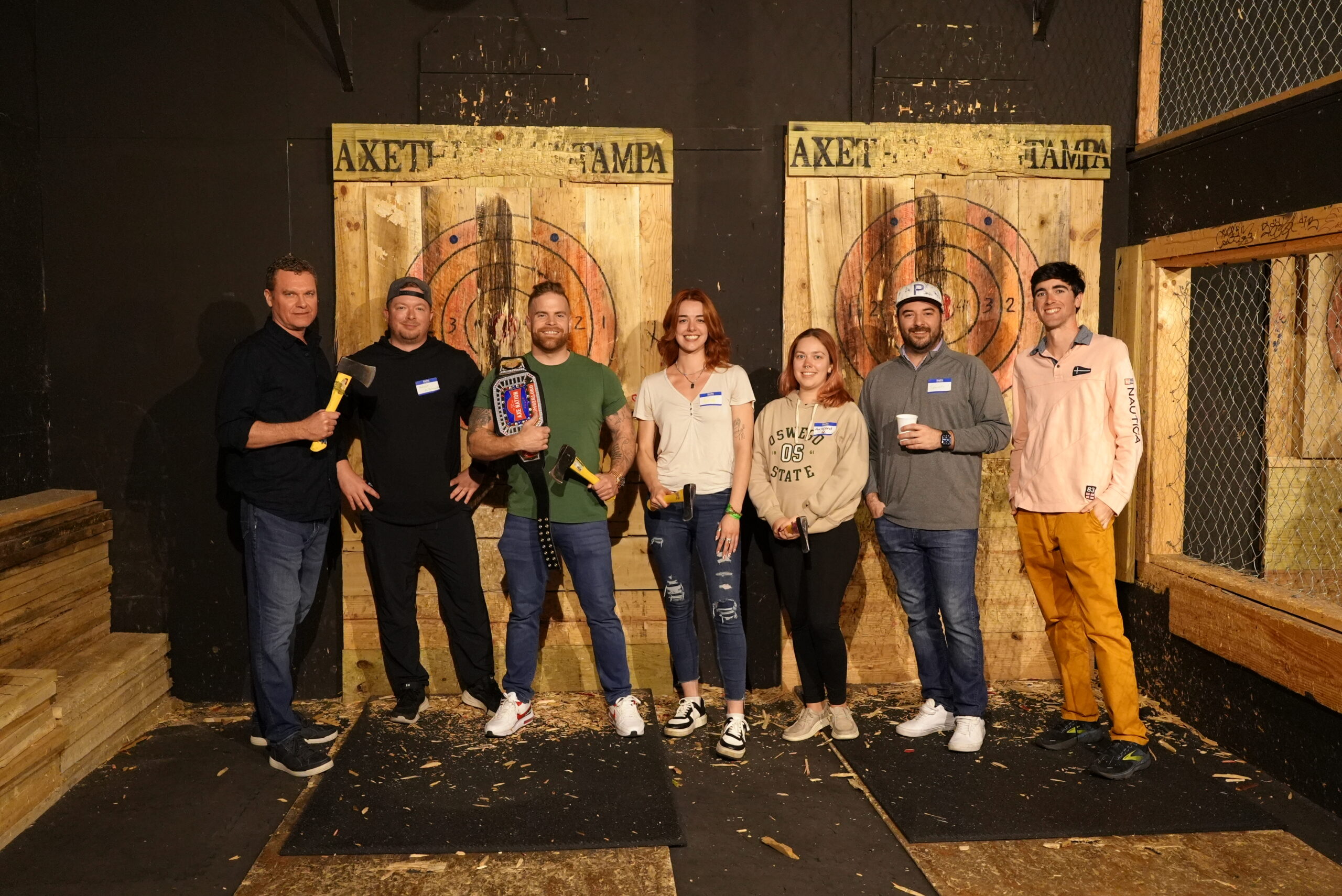 Group of people at an indoor axe throwing venue posing for a photo.
