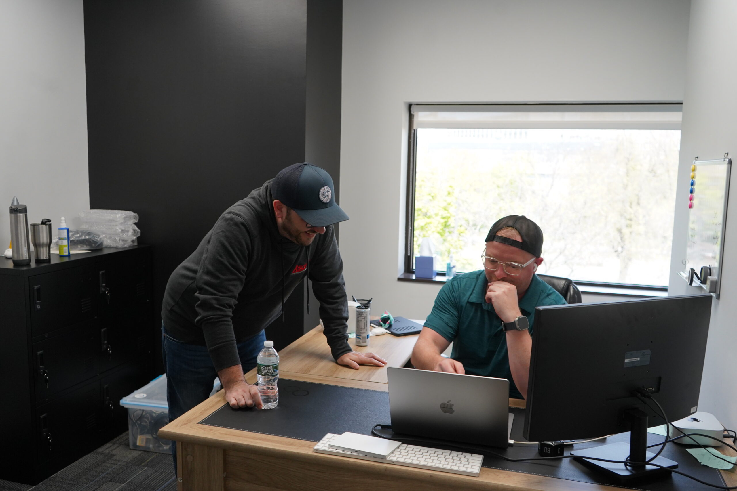 Two men collaborating over a laptop in a modern office setting.
