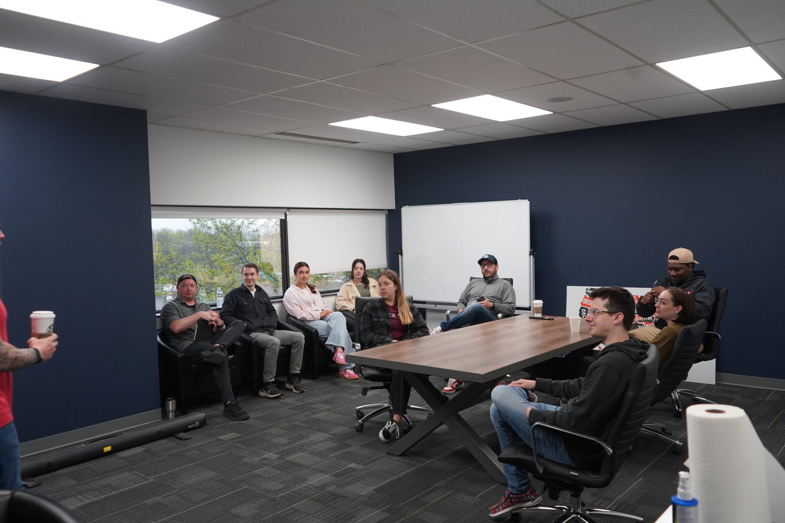 Group of people in a modern office having a meeting near a whiteboard.
