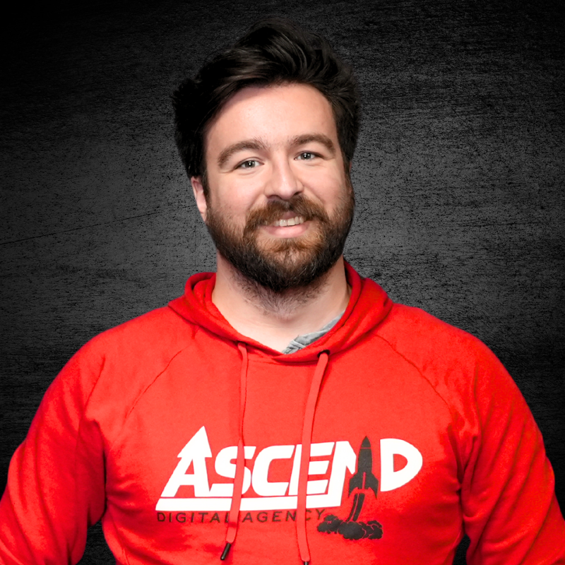 Man in red hoodie with Ascend logo against dark background.