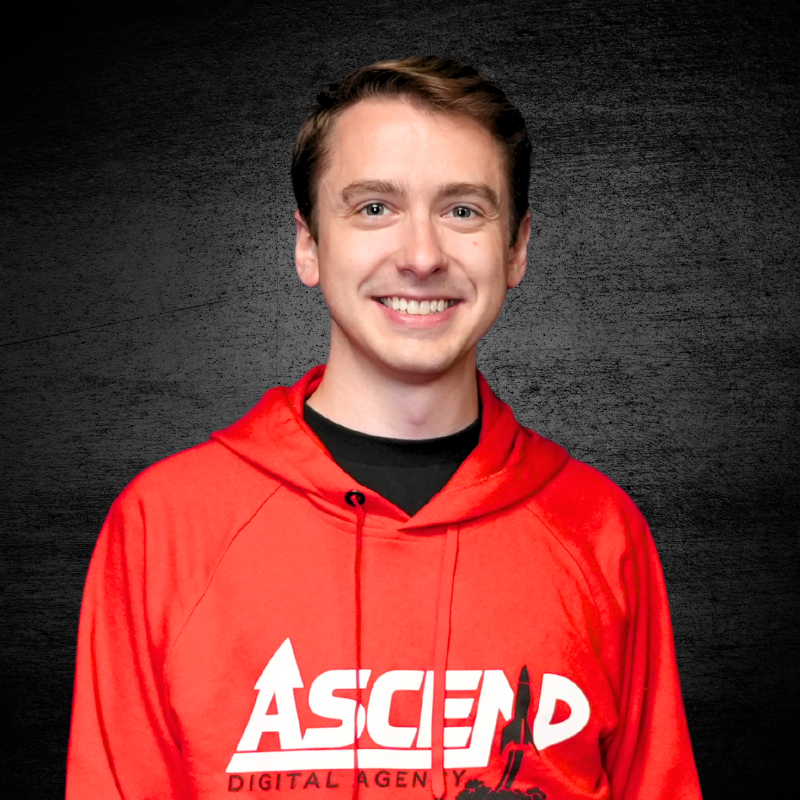Smiling person in red hoodie with Ascend branding on a textured background.