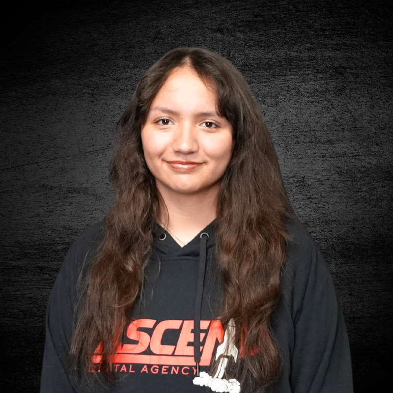 Young woman in a black hoodie with long brown hair against a dark background.