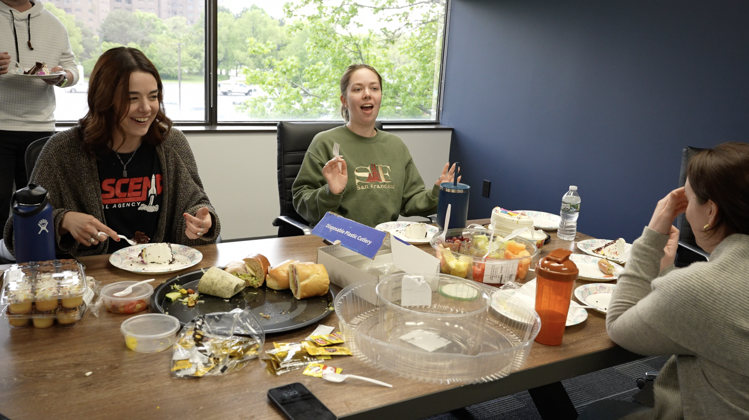 Group enjoying a casual office lunch with laughter and food on the table