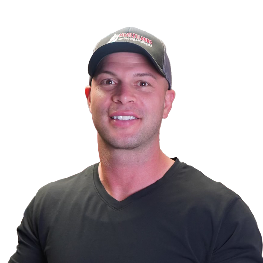 Man in black shirt and cap smiling in a room with a red wall.