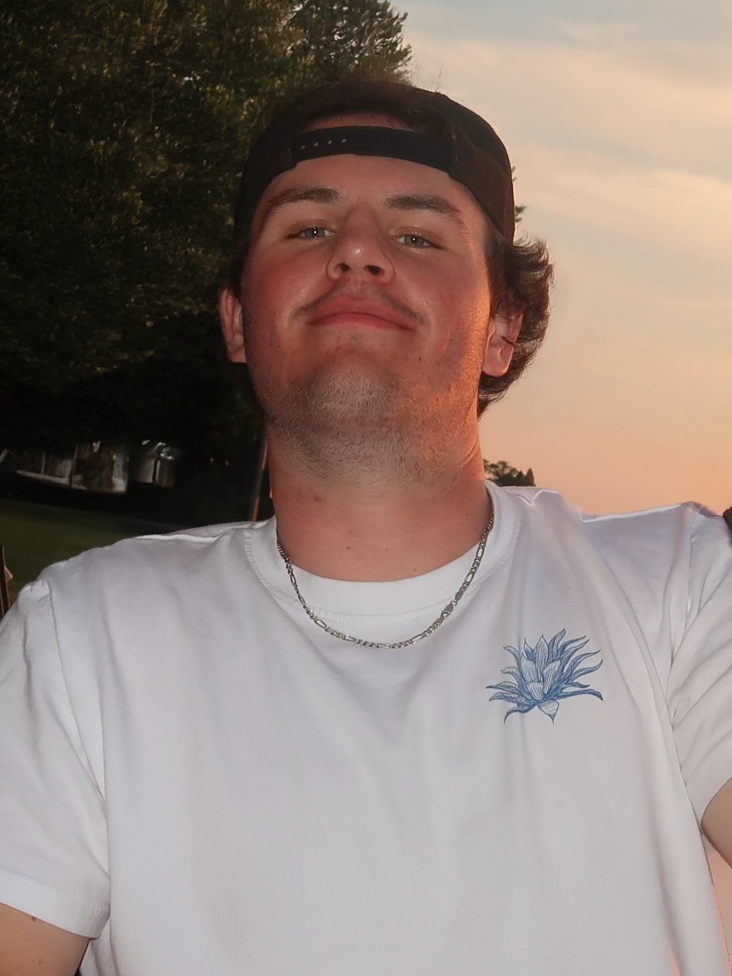 Young man in white shirt and cap outdoors at sunset