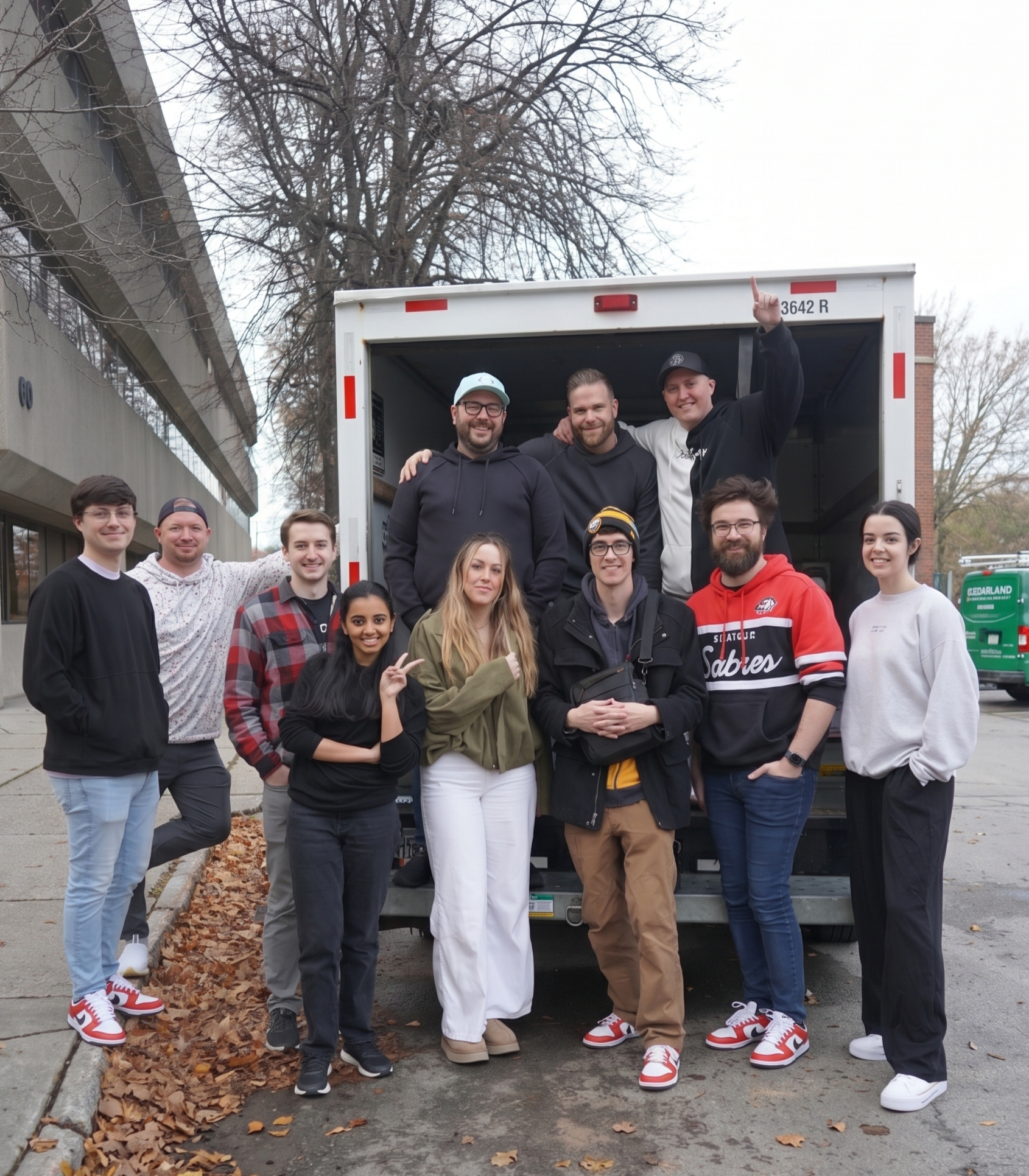 Group of people smiling in front of an open moving truck